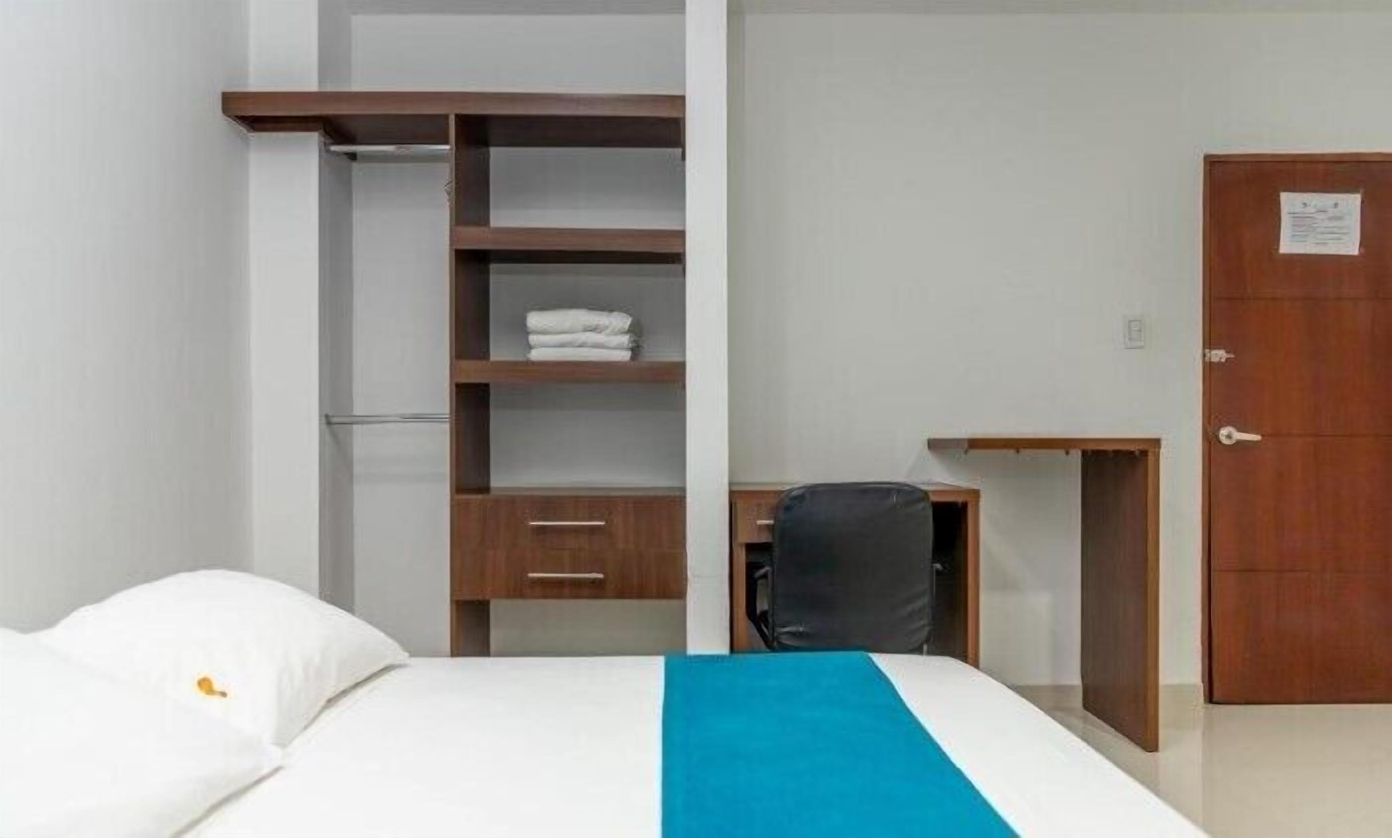 A hotel room with a bed, a desk, a chair, and a wardrobe.