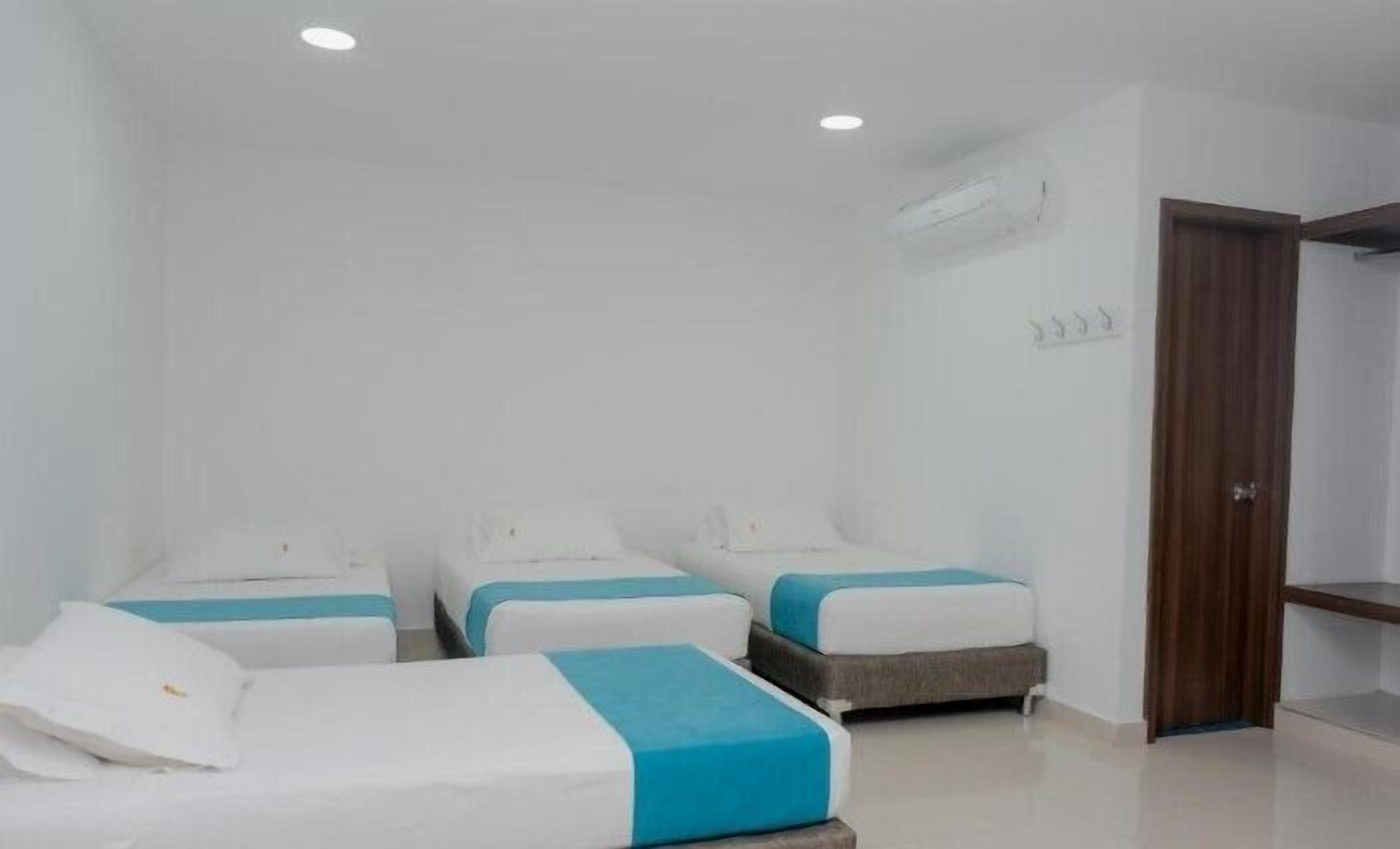 A hotel room with three beds, each with a white and blue bedspread.