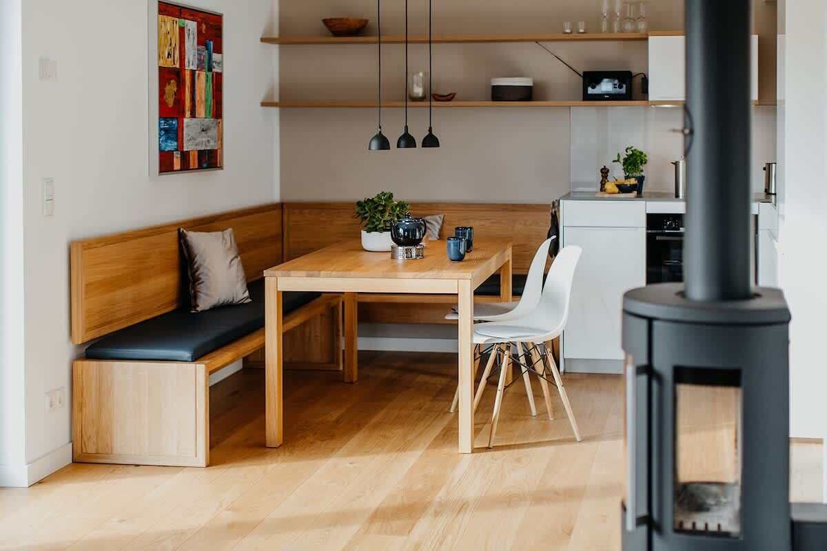 Un espace de vie chaleureux avec un banc en bois, une table à manger et un poêle à bois noir.