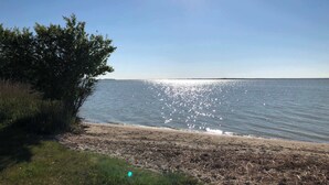A beach with a clear sky and calm water reflecting sunlight.