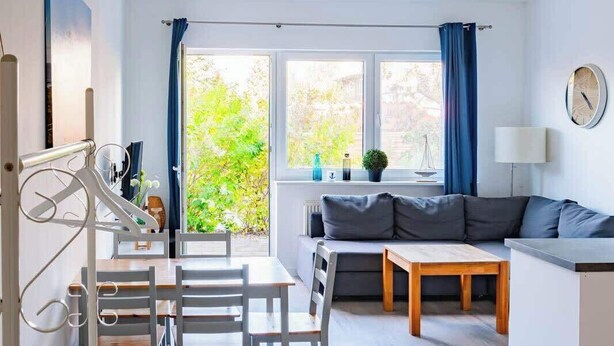 Ett modernt vardagsrum med en soffa, ett matbord med stolar och en köksdel.