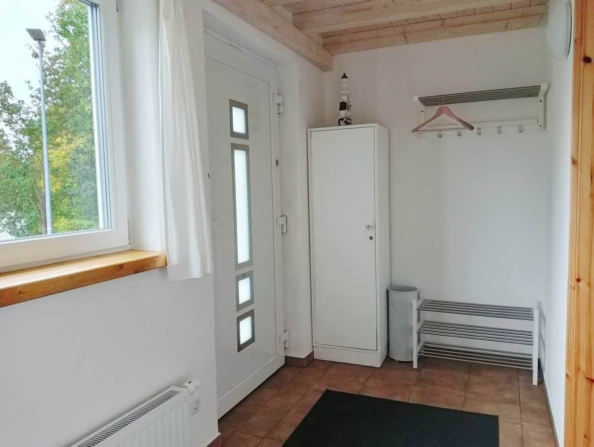 A small, bright room with a window, a radiator, a white wardrobe, and a bench.