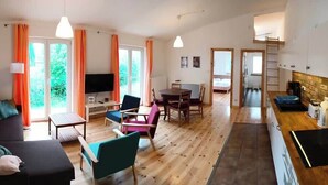 A spacious living room with a sofa, chairs, a dining table, and a kitchen area with a counter and appliances. - Blaue Sonne Devin (Stralsund)