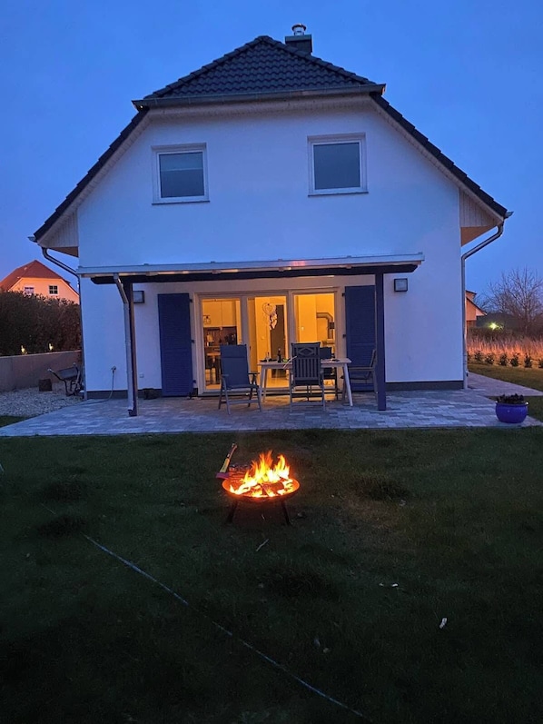 A two-story house with a covered patio area and a fire pit in the front yard. - Paula (Marlow)