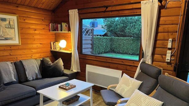 A cozy cabin interior with a sofa, armchair, and a small table.
