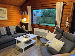 A cozy cabin interior with a sofa, armchair, and a small table.