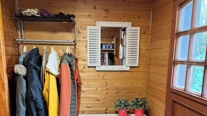 A wooden-paneled room with a coat rack, a mirror, a white shelf, and a door.