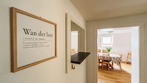 Un pasillo con texto enmarcados en la pared y un comedor con mesa y sillas.