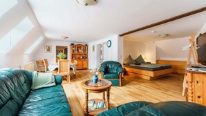Una sala de estar acogedora con un sofá verde, una mesa de centro de madera y una estantería.