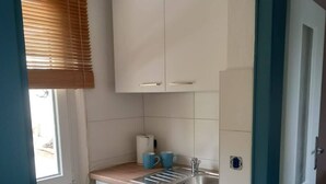 A compact kitchen with white cabinets, a stainless steel sink, and a blue countertop.