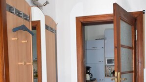 A wooden wardrobe with a mirror, a bench, and a door leading to a kitchen area. - Maaß'ens vacation home (Wildau)