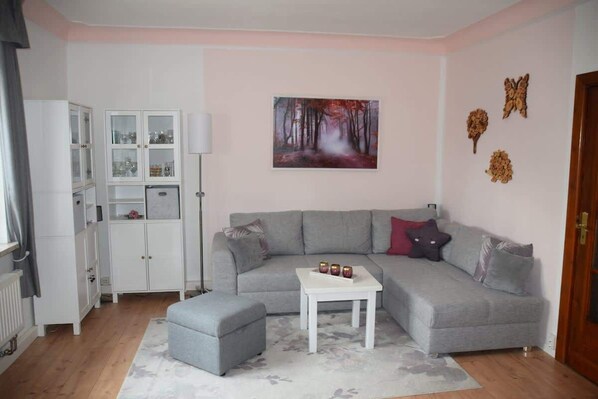 A modern living room with a grey sofa, a white coffee table, and a cabinet with glass doors. - Maaß'ens vacation home (Wildau)