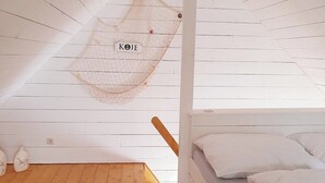 A room with a bunk bed, a hanging net, and a small rug.