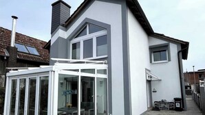 A modern two-story house with a large glass conservatory attached to the front.