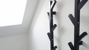 A room with a sloped ceiling, a skylight, and two black wall-mounted racks. - DUS-Loft (Düsseldorf)