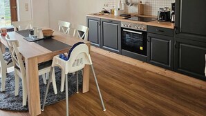 A modern kitchen with a dining area, featuring a wooden table, chairs, and a built-in oven.