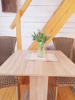 Una mesa de comedor con un florero de vidrio lleno de flores, rodeada de sillas de mimbre.