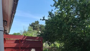 Un espace extérieur aménagé en patio, avec une table et des chaises, une clôture rouge et un pot de fleurs.