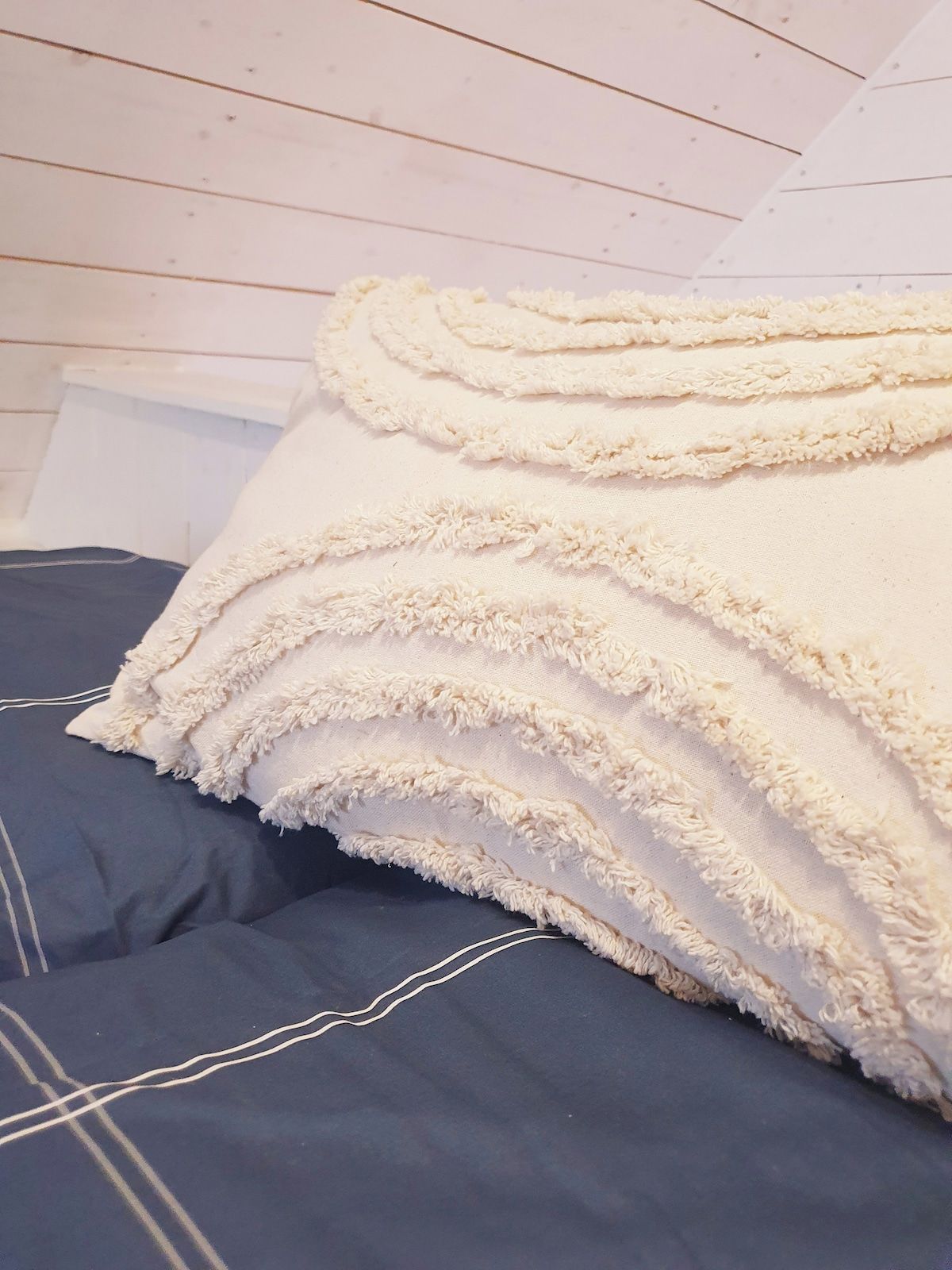 Un lit avec un drap bleu foncé et plusieurs couches de couvertures blanches et moelleuses.