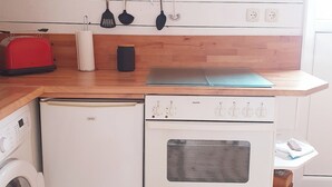 Une cuisine compacte équipée d’un lave-linge, d’un petit four, d’un grille-pain et d’une horloge murale.