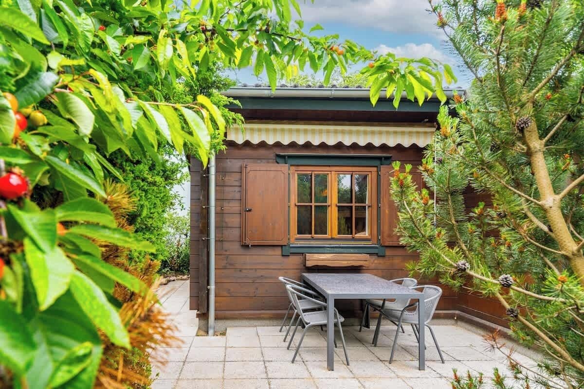 Eine Holzhütte mit einer gefliesten Terrasse, einem Tisch und Stühlen.