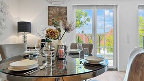 Ein moderner Essbereich mit einem Glastisch, Stühlen und einer dekorativen Tischmitte.