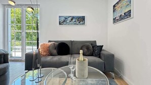 Ein modernes Wohnzimmer mit einem grauen Sofa, einem Glastisch und einer Flasche Champagner.