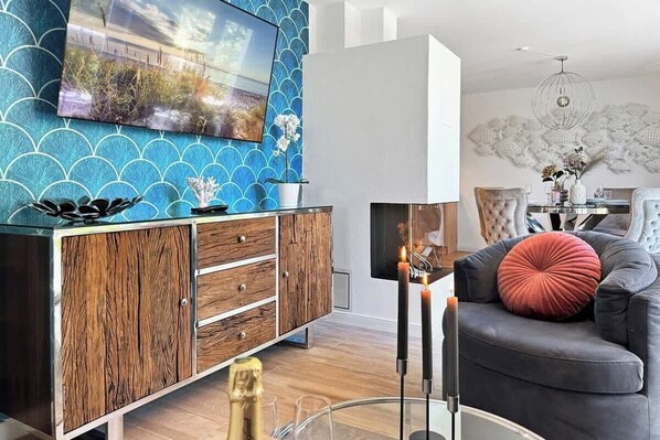 Een moderne woonkamer met een houten kast, een grijze bank en een flatscreen televisie bevestigd aan een blauwe muur.