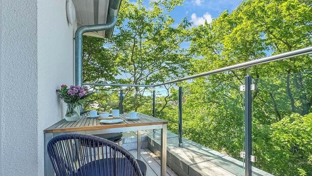 Ein Balkon mit Tisch und Stuhl, mit Blick auf eine üppige grüne Landschaft.