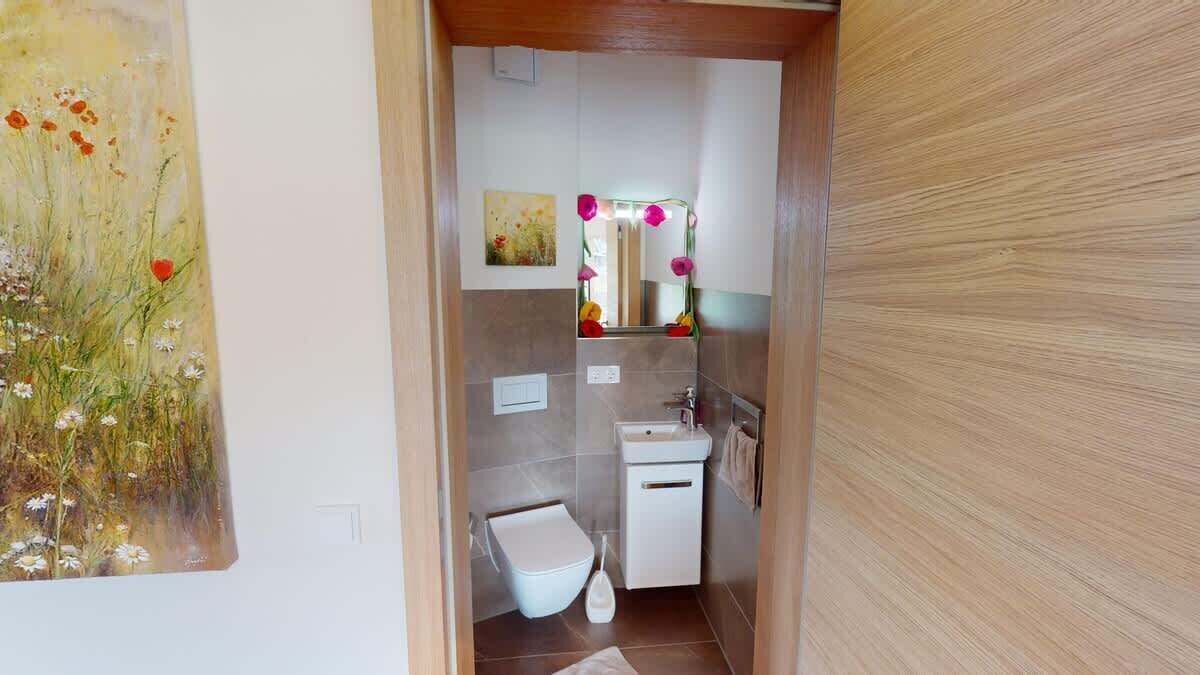 A narrow bathroom with a toilet, sink, and mirror.