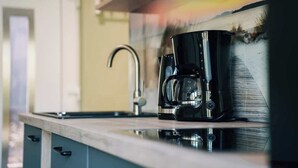 Una cocina con una cafetera moderna en la encimera, un grifo de acero inoxidable y vistas al paisaje a través de una ventana.