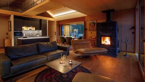 Una sala de estar moderna con chimenea, un sofá, una mesa de centro y vistas a la cocina y el comedor.