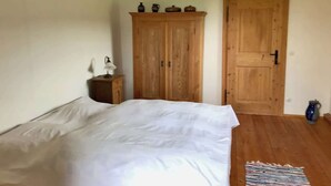Een slaapkamer met een groot bed, een houten garderobe en een klein nachtkastje.