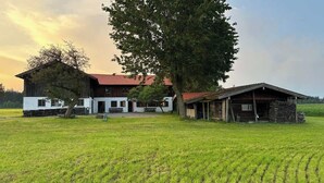 Een grote boerderij met een rood dak, een wit gedeelte en een kleiner bijgebouw.