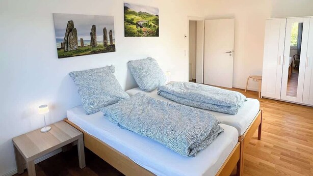 A bedroom with a double bed, a nightstand, and a wardrobe. - Buschwiesen Ausguck (Teltow)