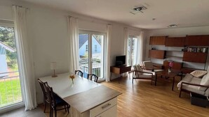 A spacious living area with a kitchen, dining table, and seating area. - Buschwiesen Ausguck (Teltow)