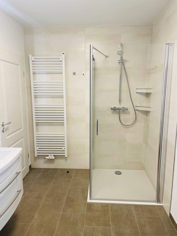 A modern bathroom with a glass-enclosed shower, a white toilet, and a towel rack.