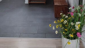Ein modernes Interieur mit einer Holzspirale, einer kleinen Holzbank und einem Blumentopf mit Blumen.