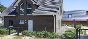 A modern two-story residential building with a dark brown exterior, a sloped roof, and a visible number '9' on the front door.