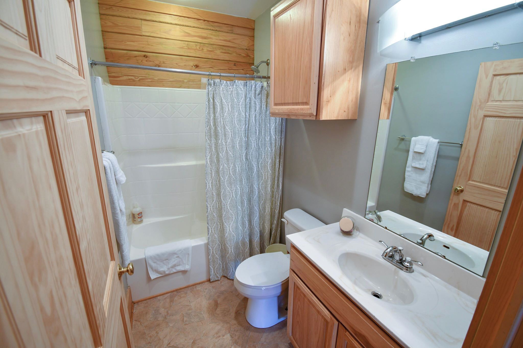 Un baño con bañera, inodoro, lavabo y armarios de madera.