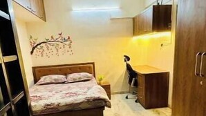 Een kleine slaapkamer met een bed, bureau en kledingkast.