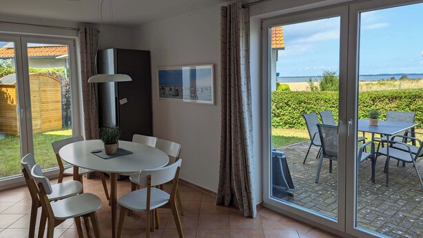 Een eethoek met een tafel en stoelen, een potplant, een plafondlamp, een deur en uitzicht op de omgeving.
