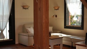 A cozy room with a wooden floor, a white sofa, a small table, and a window with curtains. - Barther  Hafensonne (Barth)