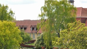 A building with a red-tiled roof and a prominent tower with a dome. - Barther  Hafensonne (Barth)