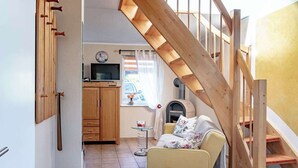 A living room with a sofa, a television, a wooden cabinet, and a staircase.
