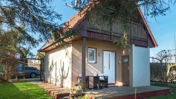 A small, single-story building with a sloped roof, a front door, and a small porch area.