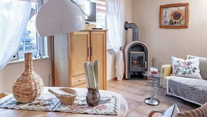 A cozy living room with a fireplace, a television, and a dining area with a table set for two.