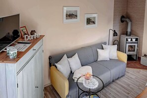 Kodikas olohuone, jossa on sohva, pieni sohvapöytä, televisio ja takka.