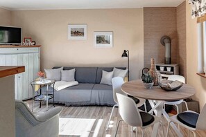 A cozy living area with a sofa, a round wooden table, and a TV on a cabinet.