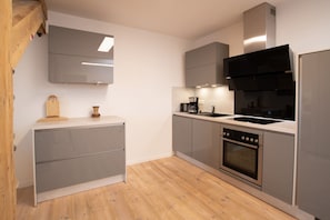 A modern kitchen with grey cabinets, a stainless steel oven, and a wooden countertop. - Exklusive Ferienwohnung Sonnensicht in Barth (Barth)